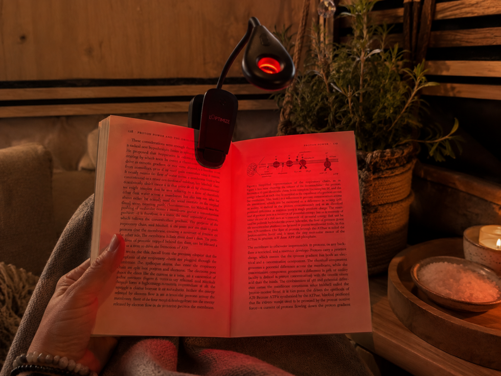 Open boek verlicht door een rood Loptimize leeslampje
